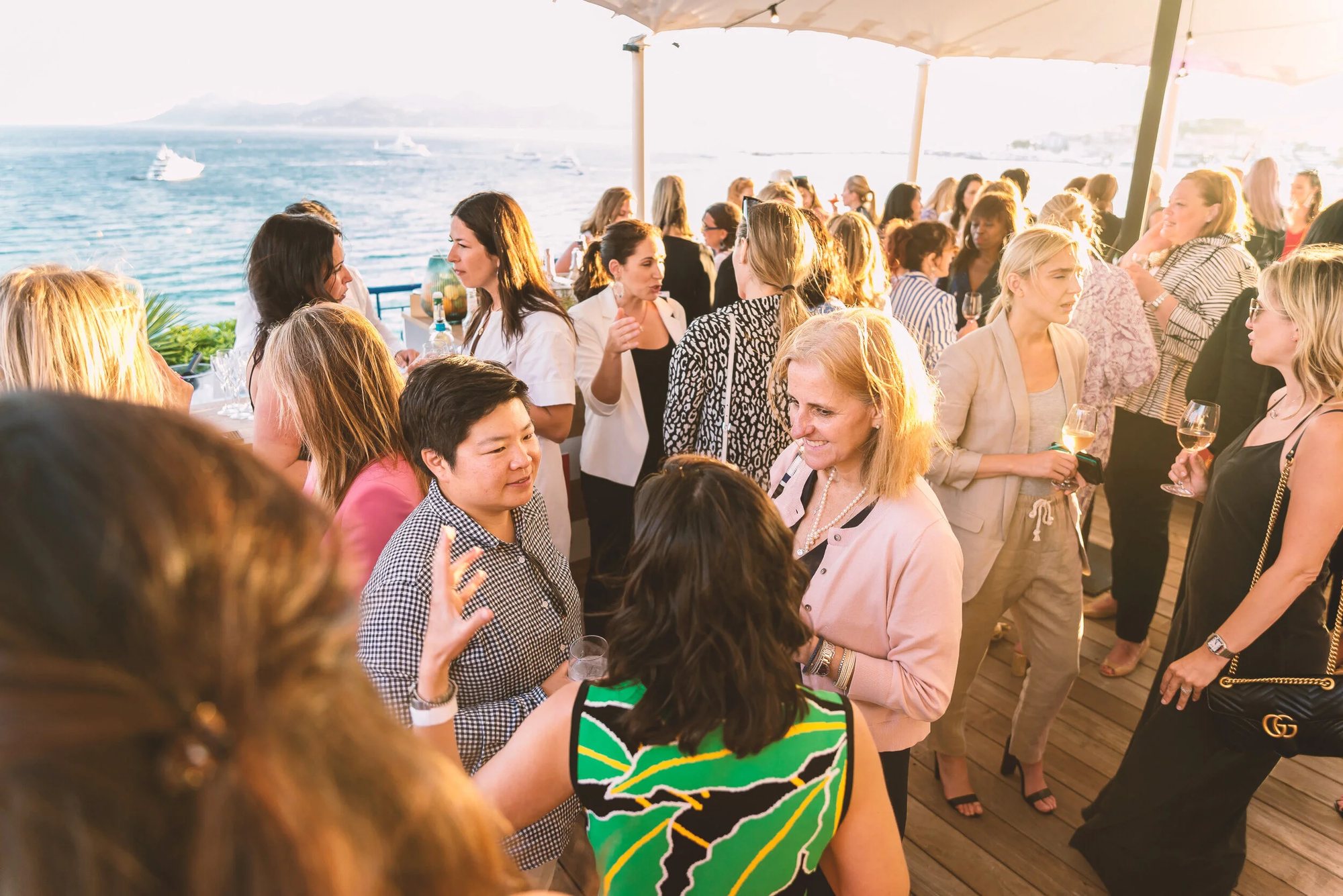 Guests talking at golden hour on a Cannes rooftop overlooking the water