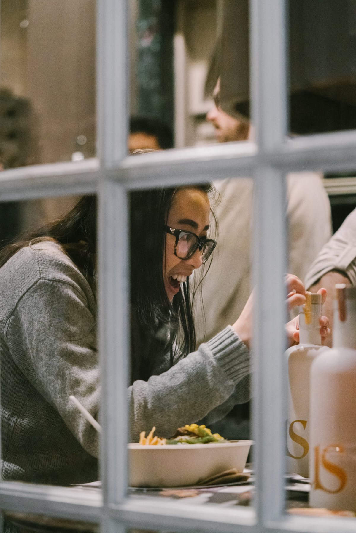 Guests seen through a window pane, sharing food