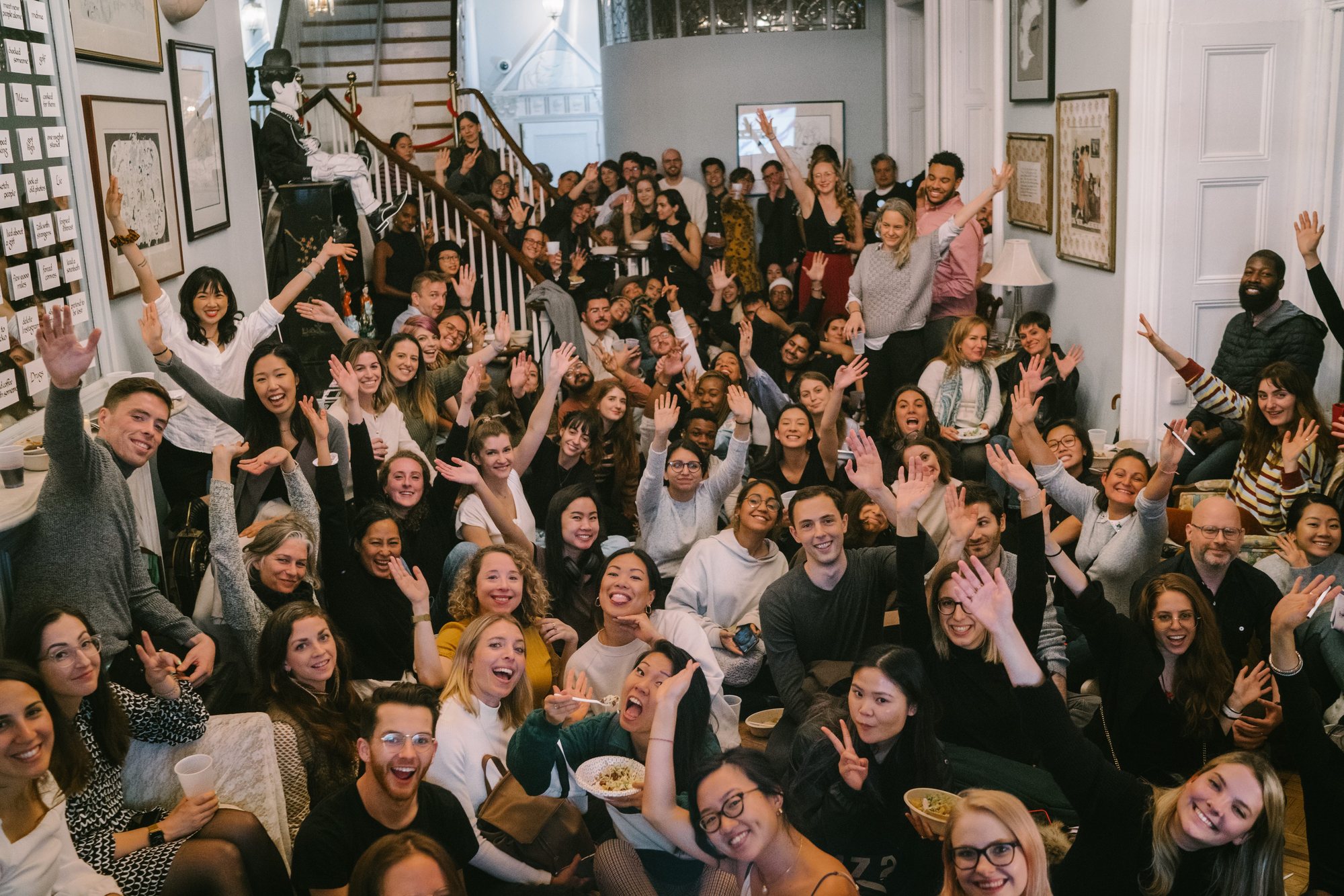 A packed room of guests cheering with their hands up at culture of