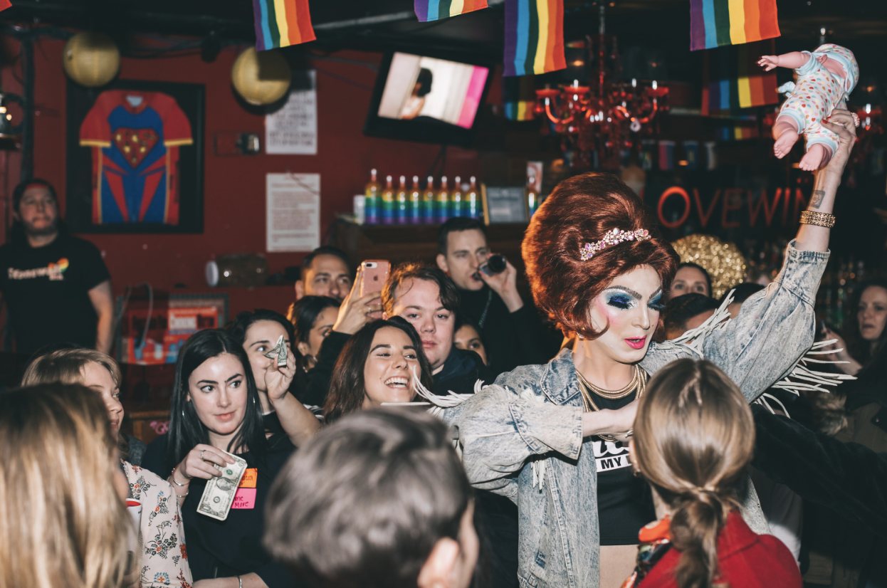 A drag queen performing in the middle of a cheering crowd