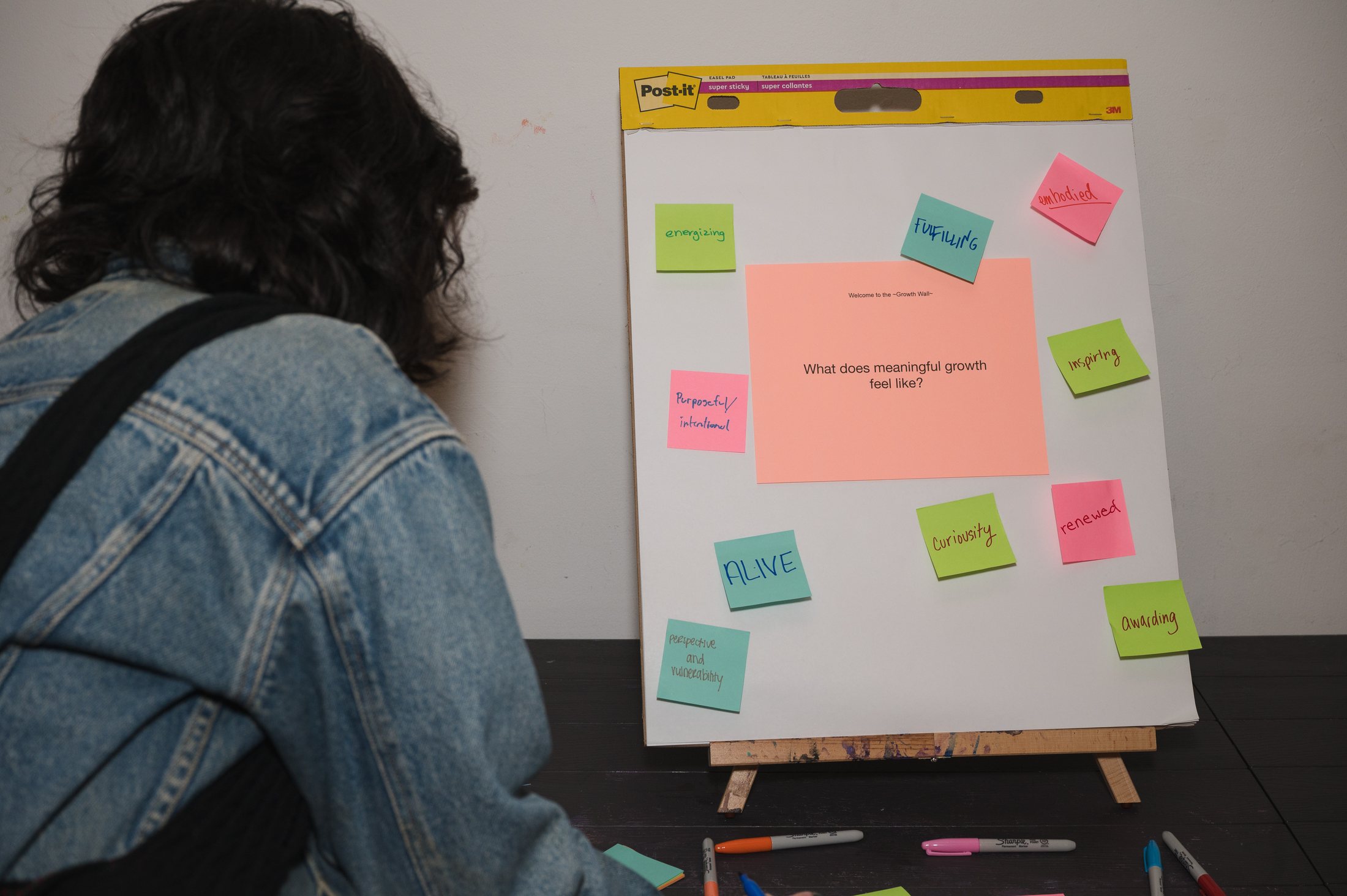 A Growth Wall easel pad asking what does meaningful growth feel like, ringed with handwritten sticky notes