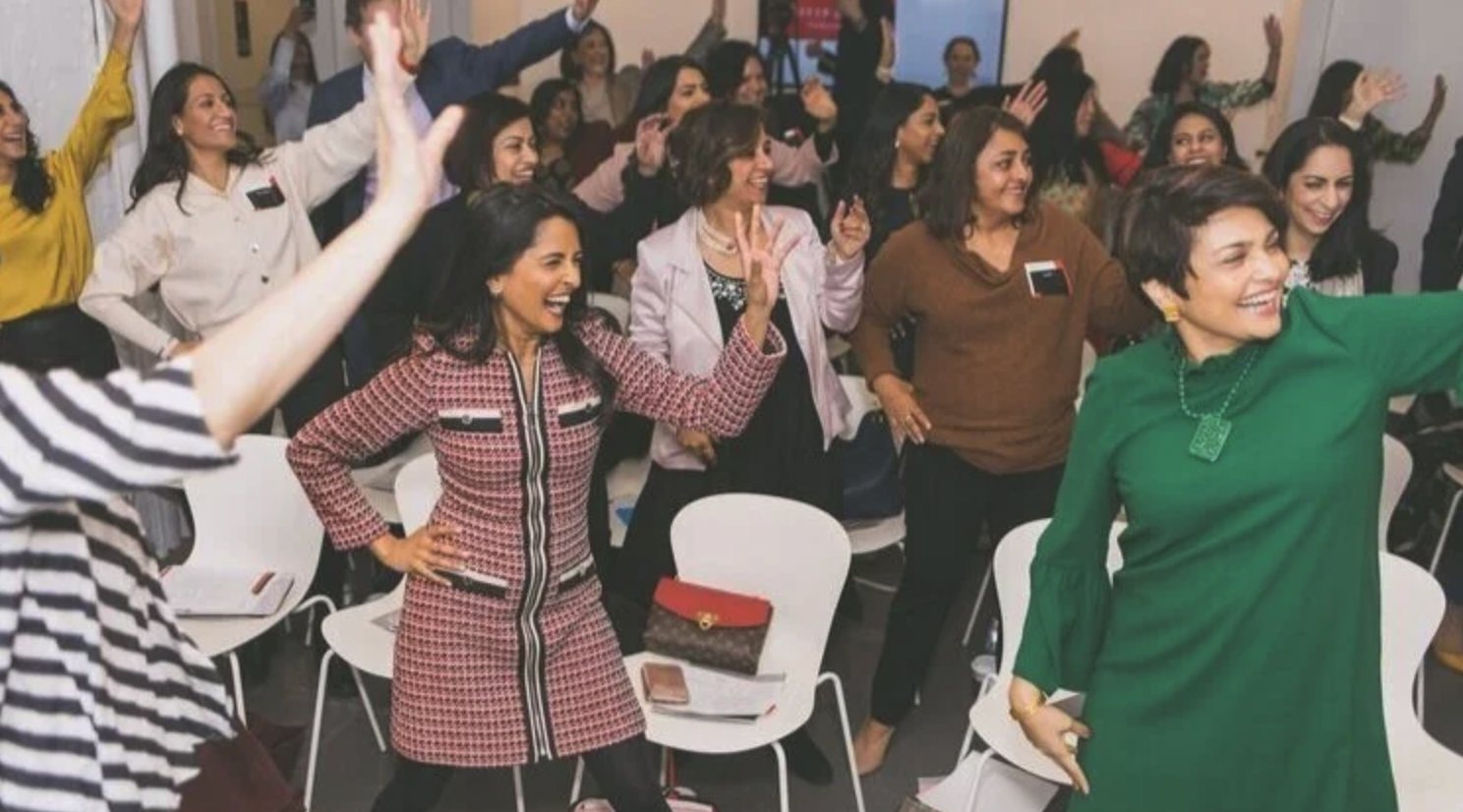 A room of guests on their feet, arms up, cheering
