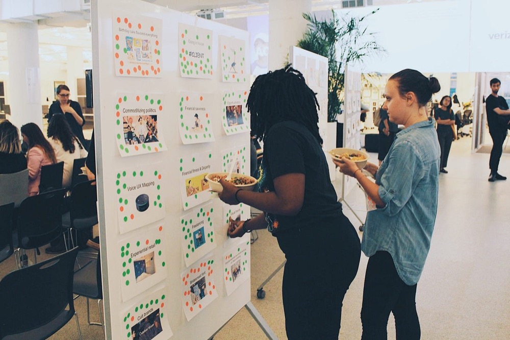 Two attendees placing stickers on a wall of trend boards
